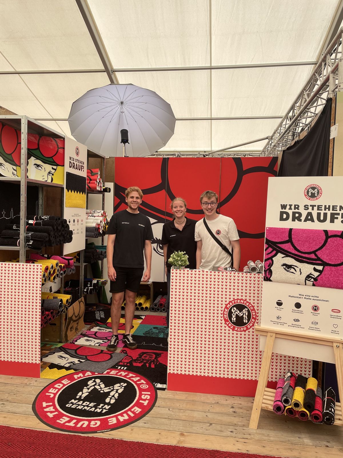 The Mattentat team with the Würth Bildungspreis, Künzelsau. The stand with the Klischee wall, 2022, and a cart of mats in the warehouse.